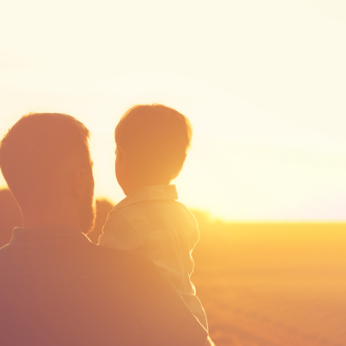 Far og søn i silhuet med solnedgang i baggrunden